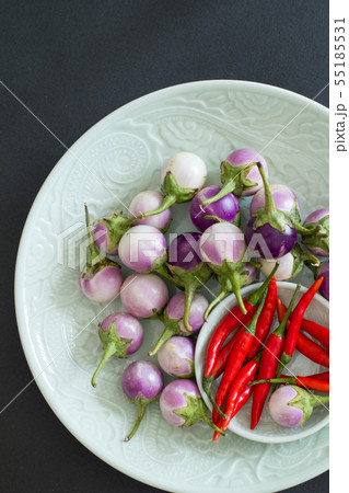 Purple Thai eggplants and hot chili peppers on a Purple Thai eggplants and hot chili peppers on a 55185531