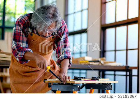 Old Asian craftsman is working with saw to cut 55185867