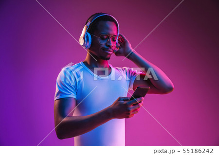 Young african-american man's listening to music in neon light Young african-american man's listening to music in neon light 55186242