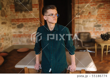 Young male artist in aprong and glasses stand in front of brick wall 55186774