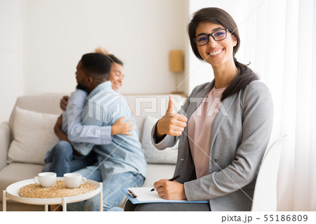 Cheerful Psychologist Gesturing Thumb Up While Happy Afro Couple Hugging Cheerful Psychologist Gesturing Thumb Up While Happy Afro Couple Hugging 55186809