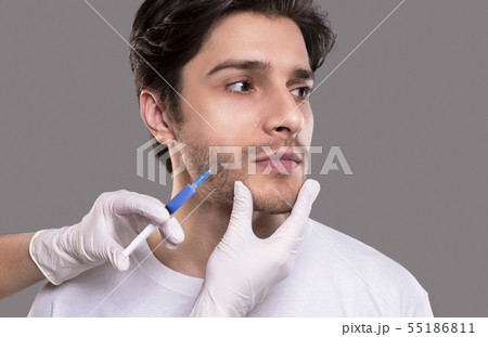 Young man getting beauty injection, grey studio background Young man getting beauty injection, grey studio background 55186811