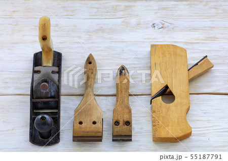 Old carpentry tools lie on a white wooden table. Old carpentry tools lie on a white wooden table. 55187791