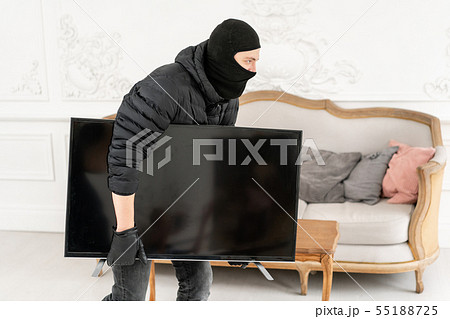 Thief with black balaclava stealing modern expensive television. Luxury apartment with stucco. Man 55188725