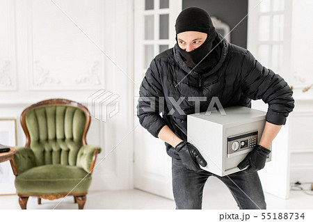 The burglar commits a crime in Luxury apartment with stucco. Thief with black balaclava stealing 55188734