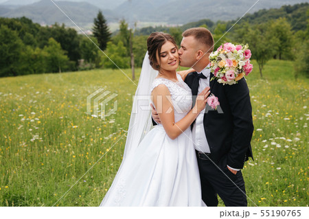 Groom and bride stand in the fiels. Background of mountains. Happy couple 55190765