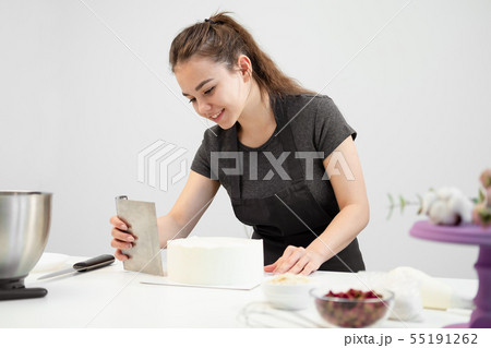 White smooth cylindrical cake blank. The confectioner creates the shape of a pastry spatula. 55191262