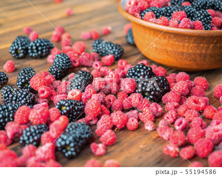 Black and red berries laying on brown table, close Black and red berries laying on brown table, close 55194586