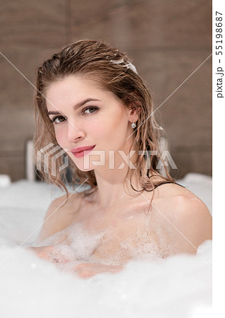 Attractive blonde woman lying in bathtub in foam in hotel. Attractive blonde woman lying in bathtub in foam in hotel. 55198687