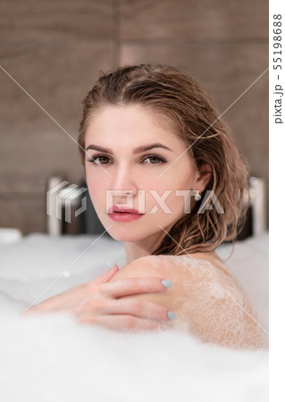 Attractive blonde woman lying in bathtub in foam in hotel. 55198688