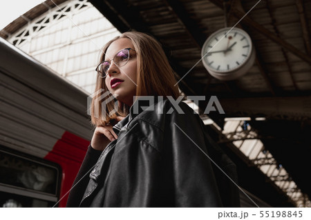 Attractive young woman millenial in black clothes and a hat and glasses at the railway station next Attractive young woman millenial in black clothes and a hat and glasses at the railway station next 55198845