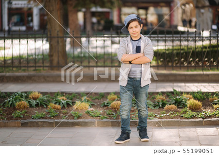Stylish little school boy in blue cap posing outside for photo. Boy walking in the city in sping 55199051