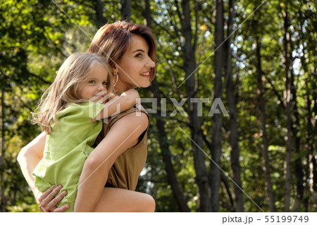Family happiness. Cute young daughter riding her mom's back, on the nature in the park. Concept mom 55199749