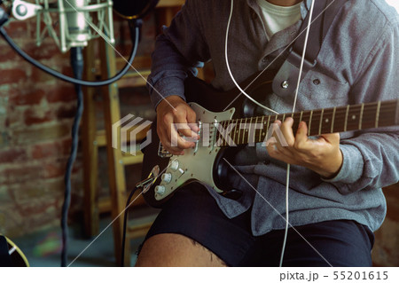 Young man recording music, playing guitar and singing at home 55201615