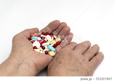 Old hands hold multicolored medical pills. Old hands hold multicolored medical pills. 55207407