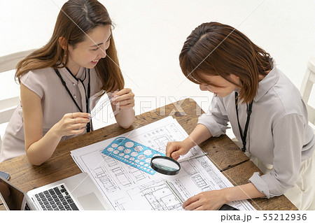 リフォーム工事の現場事務所で図面納まりを確認し仕上げの指示をする設計事務所の一級建築士女性工事監理者の写真素材 リフォーム工事の現場事務所で図面納まりを確認し仕上げの指示をする設計事務所の一級建築士女性工事監理者の写真素材