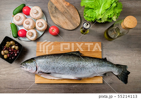 Top view keta fish, whole on the cutting board of the kitchen table next to olives tomatoes and Top view keta fish, whole on the cutting board of the kitchen table next to olives tomatoes and 55214113