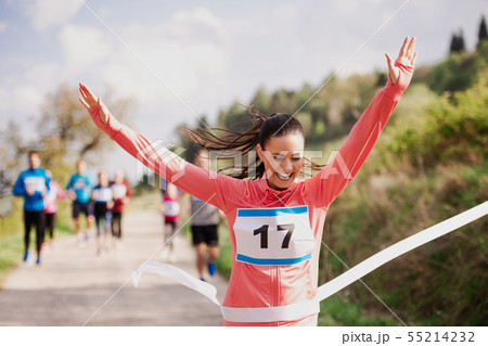 Young woman runner crossing finish line in a race competition in nature. 55214232