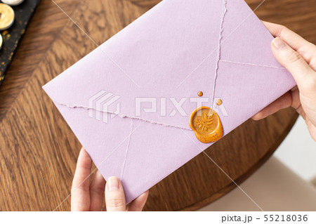 A woman is holding a welcome envelope with a wax seal, a gift certificate, a postcard, a wedding A woman is holding a welcome envelope with a wax seal, a gift certificate, a postcard, a wedding 55218036
