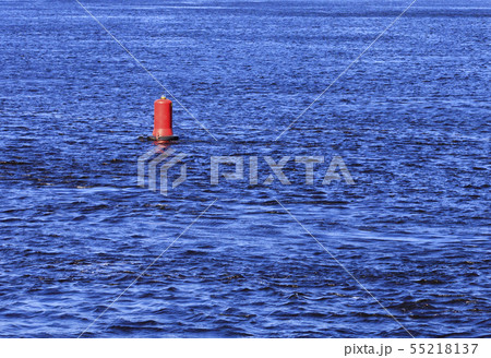 Red buoy bobs on the blue waves of a wide river. Red buoy bobs on the blue waves of a wide river. 55218137