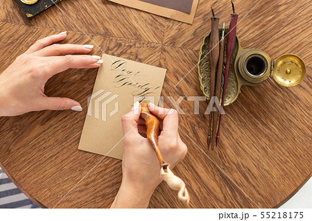 Calligrapher is holding a pen with ink. The girl writes a letter in handwritten font. Creative Calligrapher is holding a pen with ink. The girl writes a letter in handwritten font. Creative 55218175