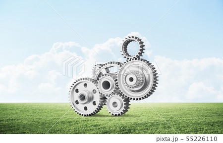 Abstract mechanism with cogwheels on green meadow Abstract mechanism with cogwheels on green meadow 55226110