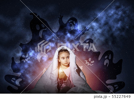 Scared girl with flashlight under blanket Scared girl with flashlight under blanket 55227649