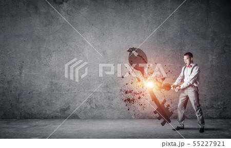 Breaking through access concept with man in room crashing concrete key Breaking through access concept with man in room crashing concrete key 55227921
