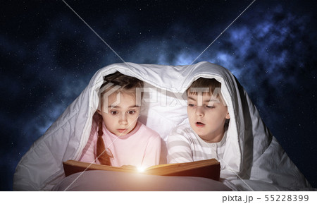 Children reading scary stories in bed Children reading scary stories in bed 55228399