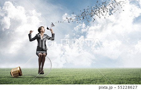 Woman with megaphone sitting on big light bulb Woman with megaphone sitting on big light bulb 55228627