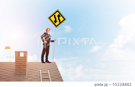 Engineer man on brick roof with sign in hands. Mixed media Engineer man on brick roof with sign in hands. Mixed media 55228802