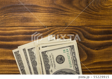 One hundred dollars bills on wooden desk One hundred dollars bills on wooden desk 55229915