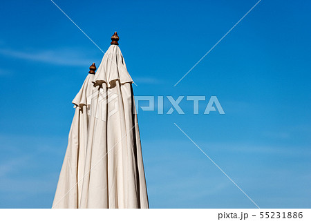 Closed beach umbrellas on blue sky Closed beach umbrellas on blue sky 55231886