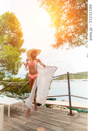 Young beautiful woman drinking white wine relaxing on open terrace enjoying view of the Young beautiful woman drinking white wine relaxing on open terrace enjoying view of the 55232389