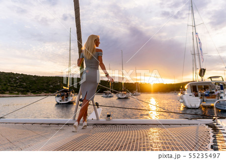 beautiful sexy woman in dress relaxing on a yacht front at sunset 55235497