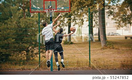 Young men playing basketball on the sports ground outdoors - protecting the basketball hoop from 55247852