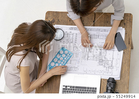 申請図面を広げて建設現場の建物詳細納まり寸法の確認を指導指示する先輩上司女性ビジネスマン 申請図面を広げて建設現場の建物詳細納まり寸法の確認を指導指示する先輩上司女性ビジネスマン 55249914