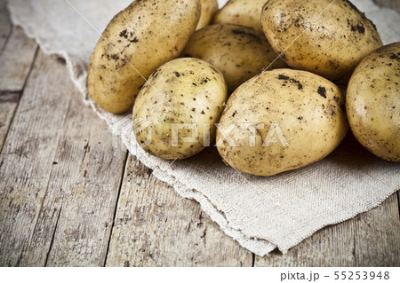 Fresh organic dirty potatoes heap closeup on linen Fresh organic dirty potatoes heap closeup on linen 55253948