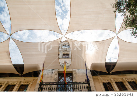 マヨルカ島の街並み　クリーム色の壁の石造りの建物と日除け用のクリーム色のシートとまぶしい太陽 55261943