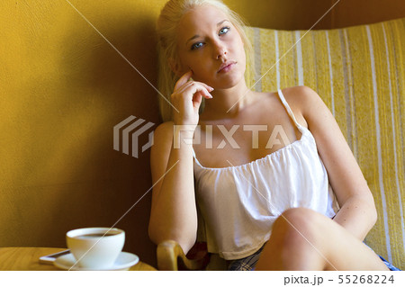 Pensive young woman at cafe with coffee and smartphone Pensive young woman at cafe with coffee and smartphone 55268224
