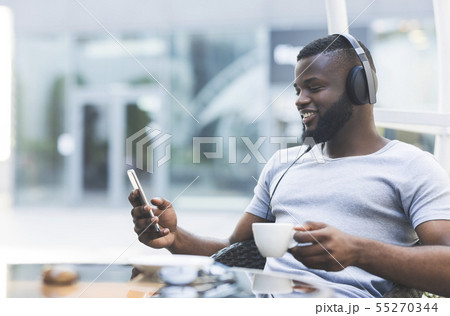 Handsome african guy in headphones with cellphone Handsome african guy in headphones with cellphone 55270344