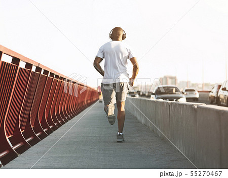 Sporty african american man running along the bridge Sporty african american man running along the bridge 55270467
