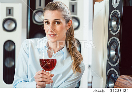Woman having glass of wine in front of Hi-Fi speakers Woman having glass of wine in front of Hi-Fi speakers 55283424
