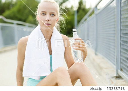 Smiling runner sitting on the ground and takes a break Smiling runner sitting on the ground and takes a break 55283718