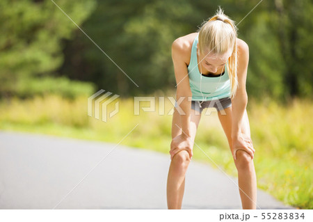 Woman leaning on knees and catch breath after stamina workout 55283834