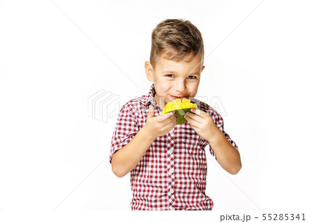 handsome boy in a red shirt is eating a mango 55285341
