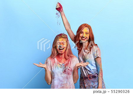 funny ginger girl throwing colored powder on her friend's head 55290326