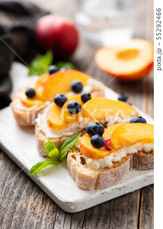 Bruschetta or appetizer toast with peach, ricotta, blueberries 55292466
