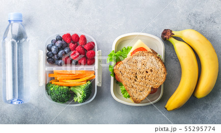 School lunch box with sandwich vegetables water almonds and fruits on grey table healthy 55295774