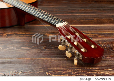 Head of guitar on textured wooden surface. 55299419